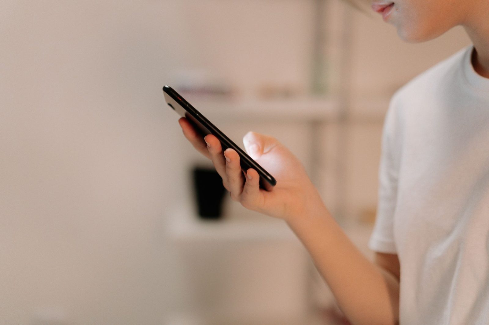 Person im weißen T-Shirt hält ein Smartphone in der Hand und liest eine Nachricht auf dem Bildschirm
