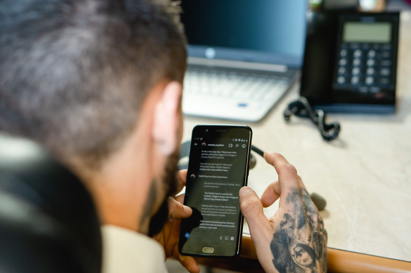 Mężczyzna trzymający smartfon z wyświetloną konwersacją SMS.