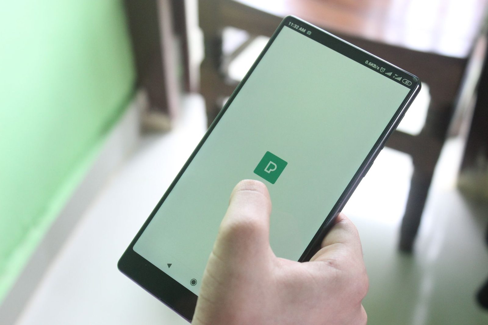 Mano che tiene uno smartphone il cui schermo mostra l'apertura di un'applicazione, il pollice sullo schermo