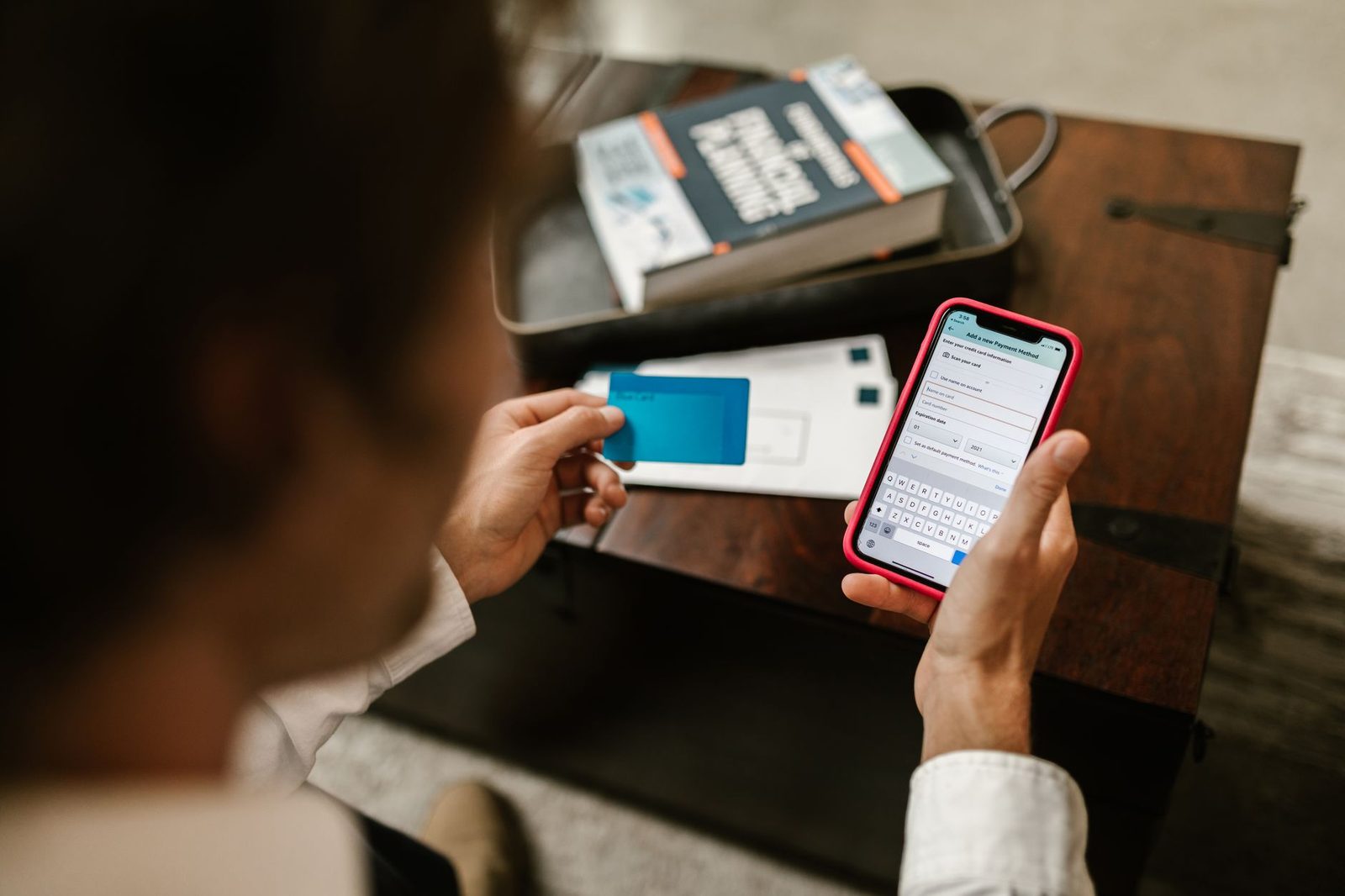 Homme tenant une carte bancaire et saisissant ses données de paiement sur un smartphone