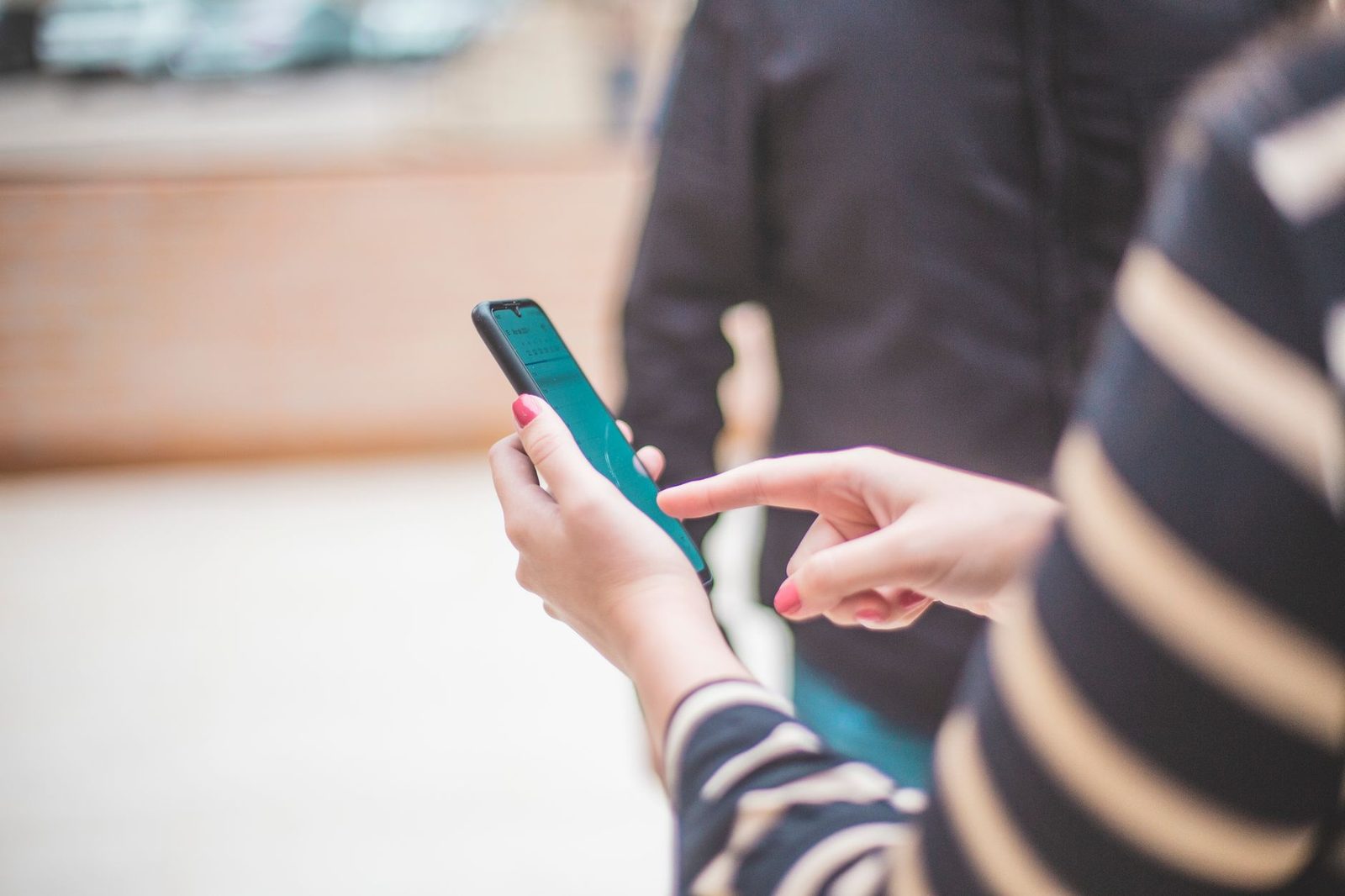 Nahaufnahme der Hände einer Frau, die auf der Straße ein Smartphone hält und darauf schaut