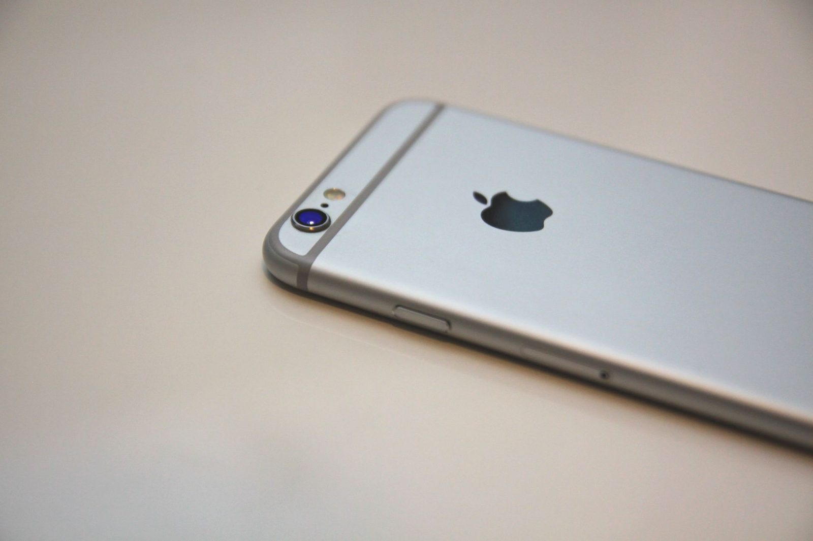 Close-up of the back of a silver smartphone resting on a white surface